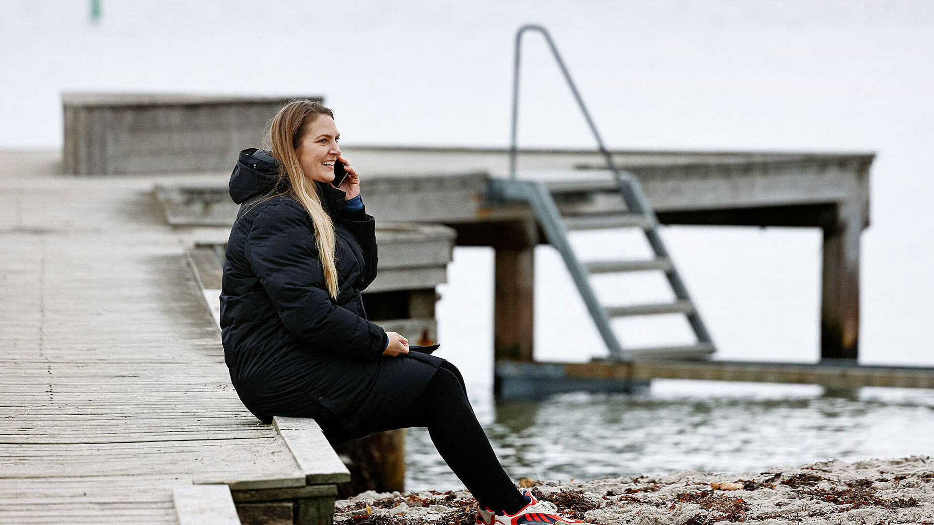 TDC NET Kvinde Ved Strand Siddende Pa Badebro Mobil Low Srgb